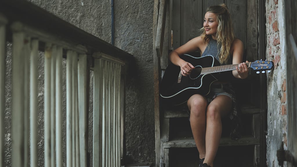 giovinezza editoriale 1024 - Photo by agnes talalaev from Pexels https://www.pexels.com/photo/woman-wearing-gray-tank-top-playing-black-cutaway-acoustic-guitar-698539/